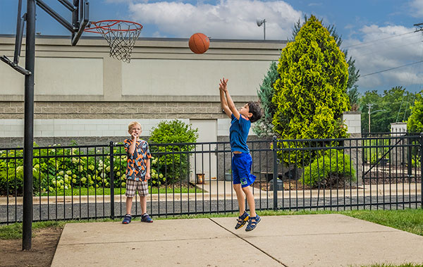 Two elementary students playing basketball outside