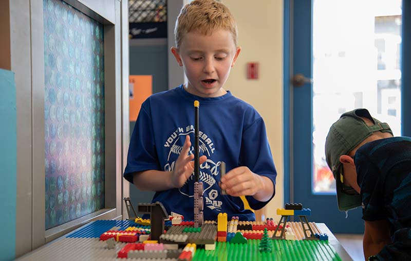 A young boy playing with Legos at a table