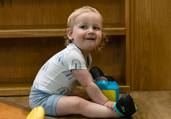 A toddler sitting on classroom floor playing with toys